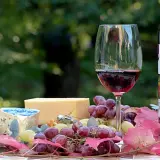 Un verre de vin rouge, du fromage et des raisins, une belle composition pour un apéritif.