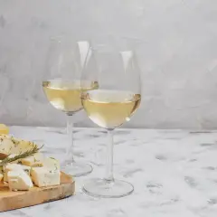 Deux verres de vin blanc pétillant, accompagnés d'une sélection de fromages sur une planche en bois.