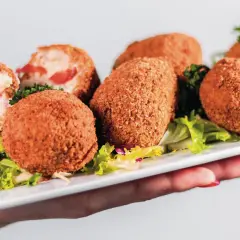 Assiette de croquetas de jambon dorées et croustillantes, garnie de salade verte.