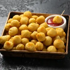 Un plateau rempli de pommes dauphine dorées et croustillantes, prêtes à être trempées dans une sauce tomate.