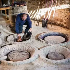 Un homme verse du jus de raisin dans une cuve en terre, peut-être pour recréer la méthode ancestrale qui a inventé le vin.