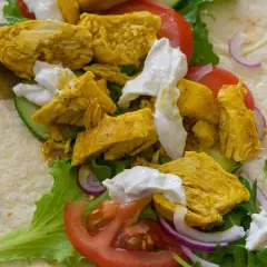 Un délicieux chawarma poulet garni de légumes frais et de sauce blanche crémeuse, prêt à être dégusté.