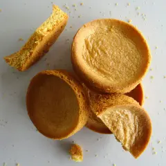 Des biscuits sablés bretons éparpillés, certains entiers, d'autres brisés, sur un fond clair.