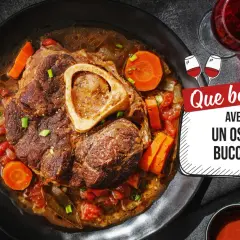 Un plat d'osso bucco savoureux, avec carottes et tomates, servi dans une assiette noire. La question "Que boire avec un osso bucco ?" est affichée à côté d'un verre de vin rouge.