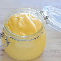 Un pot en verre ouvert révèle une mayonnaise onctueuse, faite maison avec de la mayonnaise huile d'olive.
