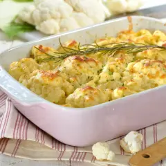 Un plat de gratin de chou-fleur doré et gratiné, garni de romarin frais, prêt à être dégusté.