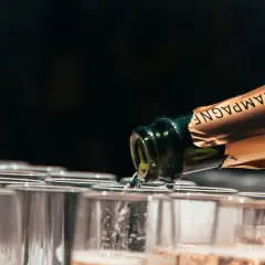 Une bouteille de champagne verse dans des flûtes alignées. Le choix idéal pour quel champagne choisir pour l'apéritif.
