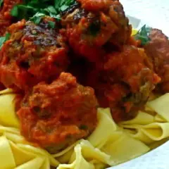Boulettes de viande italienne savoureuses en sauce tomate, servies sur des pâtes fraîches. Une recette parfaite pour un repas réconfortant.