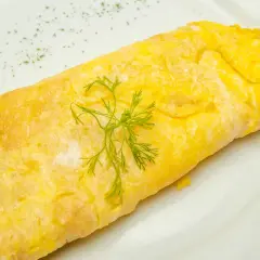Une omelette au thon, dorée et moelleuse, garnie d'aneth frais sur une assiette blanche. Un délice simple et savoureux.