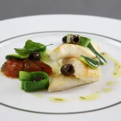 Délicieux filet de saint pierre poêlé, servi avec une concassée de tomates, des rubans de courgette et des olives noires.