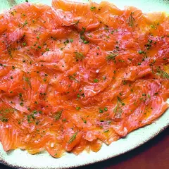 Délicieux carpaccio de saumon finement tranché, parsemé d'aneth frais et de ciboulette ciselée. Un plat léger et savoureux.