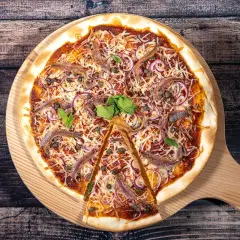 Une pizza savoureuse aux anchois, oignons rouges et câpres, garnie de fromage râpé et de basilic frais, prête à être dégustée.