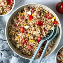 Un grand bol de salade de riz thon, garnie de tomates, maïs et œufs durs. Parfait pour un repas léger et savoureux.