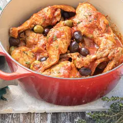 Un plat mijoté de lapin aux olives, baignant dans une sauce tomate savoureuse, garni de thym frais.