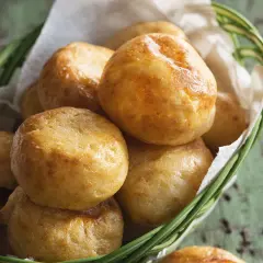Petits pains dorés, une délicieuse recette de manioc, servis dans un panier en osier garni de papier blanc.