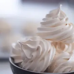 Un bol rempli de délicieuses meringues suisses, légères et aériennes, prêtes à fondre en bouche.
