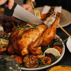 Une dinde rôtie, garnie de légumes et d'herbes, est découpée. Parfait pour savoir que boire avec une dinde farcie.