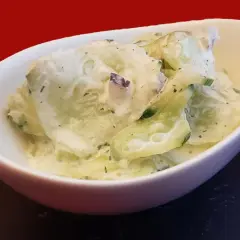 Un bol de concombre à la crème, garni d'herbes fraîches, prêt à être dégusté.