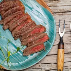 Tranches d'onglet de bœuf saignant, parsemées de gros sel, sur une assiette turquoise. Une recette simple pour un plat savoureux.