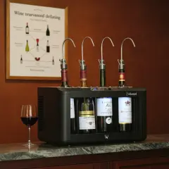 Système de conservation du vin avec quatre bouteilles ouvertes, idéal pour le temps de garde. Un verre de vin rouge à côté.