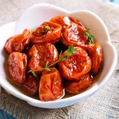 Tomates séchées confites dans de l'huile d'olive, garnies de thym frais. Une recette rapide pour un goût intense.