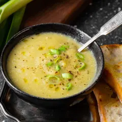 Un réconfortant velouté de poireaux pommes de terre, garni de ciboule et servi avec du pain grillé.