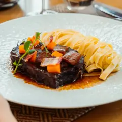 Un paleron de bœuf braisé, garni de dés de carottes et de lardons, servi avec des tagliatelles fraîches. Une recette savoureuse à découvrir.