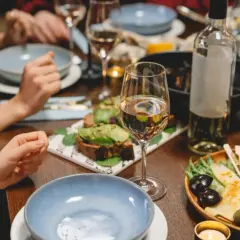 Un verre de Gewurztraminer accompagne un plateau de fromages, olives et fruits, ainsi que des toasts à l'avocat. Un repas convivial.