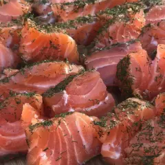 Des morceaux de saumon gravlax, parsemés d'aneth, prêts à être dégustés. Quel vin avec saumon gravlax ? Un blanc sec ou un rosé léger serait parfait.
