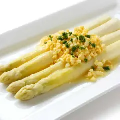 Asperges à la flamande : des asperges blanches tendres nappées d'une sauce savoureuse et garnies d'œufs brouillés et de persil frais.