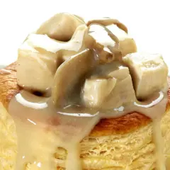 Une bouchée à la reine poulet, garnie de morceaux de volaille et d'une sauce crémeuse aux champignons, sur une pâte feuilletée dorée.