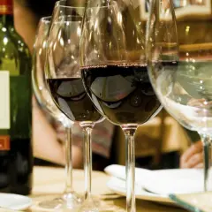 Bouteille de vin vert et verres remplis, révélant la belle couleur du vin rouge profond.