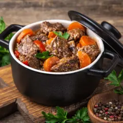 Un délicieux bœuf bourguignon mijoté dans une cocotte minute SEB, garni de carottes et de persil frais. Un plat réconfortant prêt à être dégusté.
