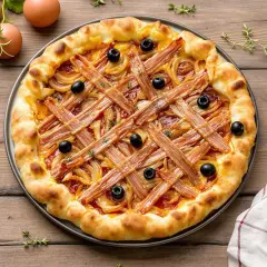 Pissaladière garnie d'oignons, d'olives et de lardons sur une pâte brisée ou feuilletée, prête à être dégustée.