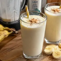 Deux verres de milkshake banane, parfaits pour une recette facile et rafraîchissante. Des bananes mûres et une touche de cannelle complètent ce délice.