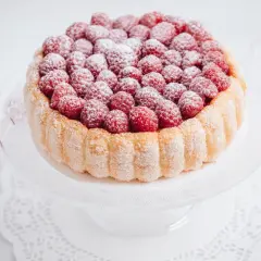 Charlotte framboise, un délice de biscuits à la cuillère et de fruits rouges, saupoudrée de sucre glace.