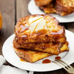 Pile de pain perdu doré, nappé de sirop et garni de beurre fondant. Un délice matinal.