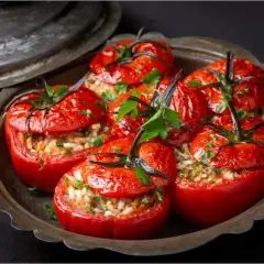 Tomates farcies au riz, garnies de persil frais, servies dans un plat en métal vieilli. Un délice simple et savoureux.