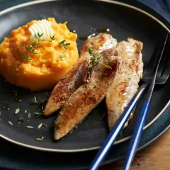 Trois aiguillettes de canard poêlées, servies avec une purée de patate douce onctueuse, garnie de thym frais et d'une noix de beurre.