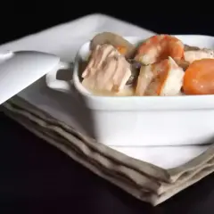 Blanquette de saumon et crevettes, nappée d'une sauce onctueuse au vin blanc, servie dans un ramequin blanc.
