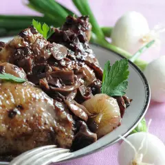 Coq au vin savoureux, garni de champignons et d'oignons. Parfait pour savoir que boire avec un coq au vin.