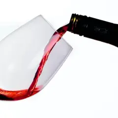 Le vin rouge, fruit d'une macération soignée, coule d'une bouteille dans un verre.