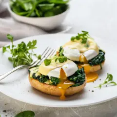 Deux œufs pochés sur des muffins anglais, recouverts de sauce hollandaise et d'épinards. Un déliceux œuf florentin prêt à être dégusté.