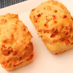 Deux petits pains dorés, un délicieux cake aux légumes, sont servis sur une assiette blanche.