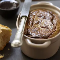 Un délicieux gâteau de foie de volaille à l'ancienne, servi avec du pain croustillant et une petite coupelle de confiture.