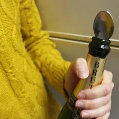 Une cuillère est insérée dans le goulot d'une bouteille de champagne pour montrer comment refermer une bouteille de champagne.
