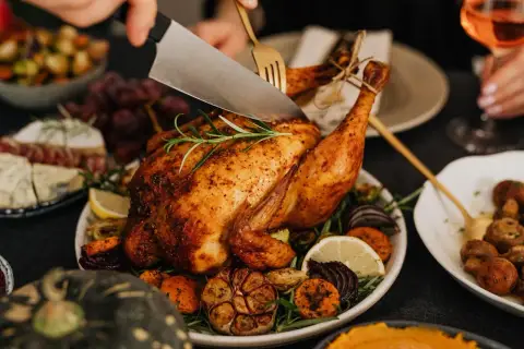 Une dinde rôtie, garnie de légumes et d'herbes, est découpée. Parfait pour savoir que boire avec une dinde farcie.