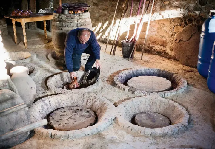Un homme verse du jus de raisin dans une cuve en terre, peut-être pour recréer la méthode ancestrale qui a inventé le vin.