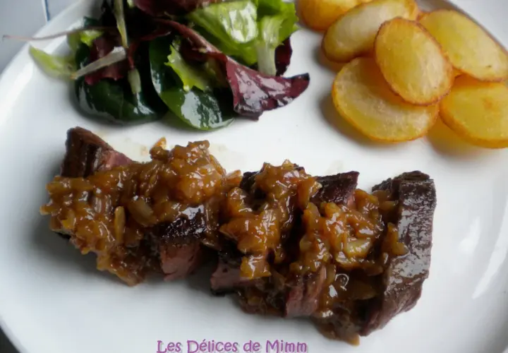 Un onglet à l'échalote, servi avec une salade verte et des pommes de terre sautées. Un plat savoureux et coloré.