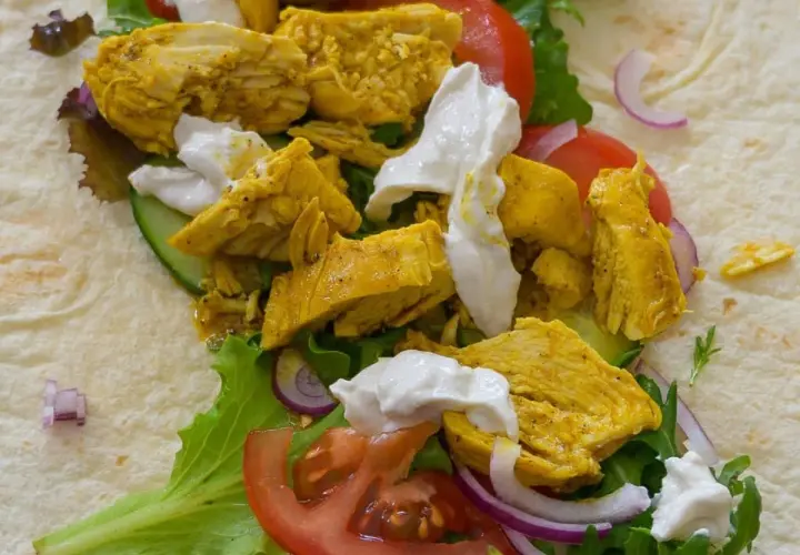 Un délicieux chawarma poulet garni de légumes frais et de sauce blanche crémeuse, prêt à être dégusté.